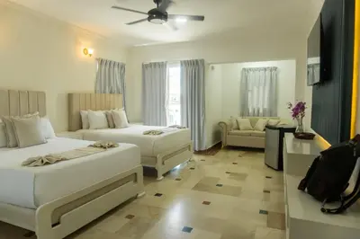 a hotel room with two beds and a couch at Hotel Checkin El Cortecito in Punta Cana