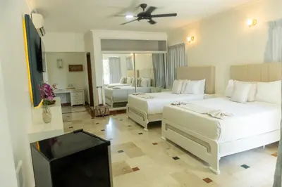 a bedroom with two beds and a flat screen tv at Hotel Checkin El Cortecito in Punta Cana
