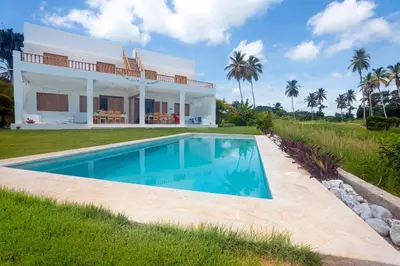 a villa with a swimming pool in front of a house at Villa Kalfu with AC in Las Galeras