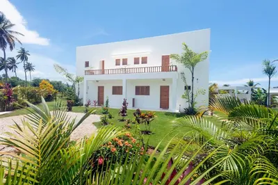 a white house with palm trees and plants at Villa Kalfu with AC in Las Galeras