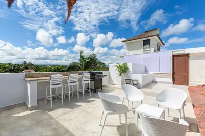 a patio with white chairs and a bar with a view at Suites at Grand Laguna Beach by Calisto Stays in Sosúa
