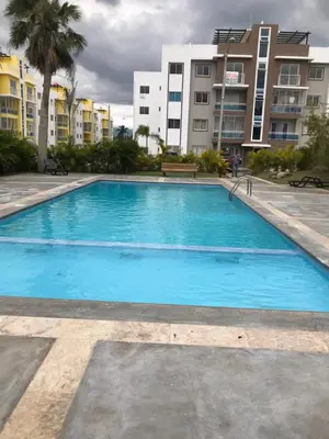 a large blue swimming pool with buildings in the background at moderno apto frente a la piscina in Santiago de los Caballeros