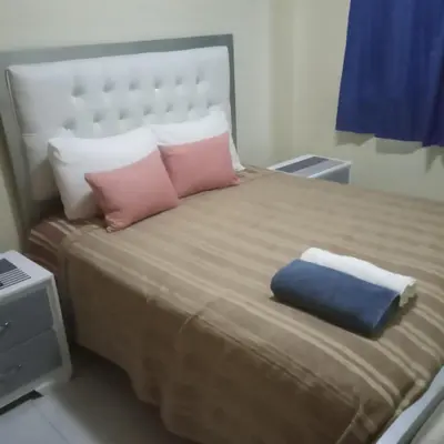 a large bed with pink and blue pillows on it at moderno apto frente a la piscina in Santiago de los Caballeros