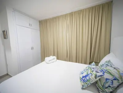 a bedroom with a white bed with a towel on it at Cozy 2br-2bt Apt Near The Beach And Main Street in Sosúa