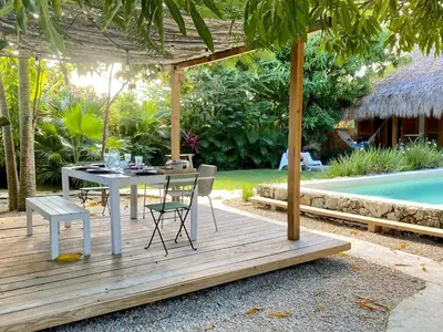 a table and chairs on a wooden deck next to a pool at Bungalow with pool and Air Conditioning near playa Macao in Punta Cana