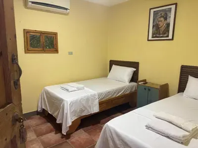 two beds in a room with yellow walls at Hotel Loro Tuerto in Santa Cruz de Barahona