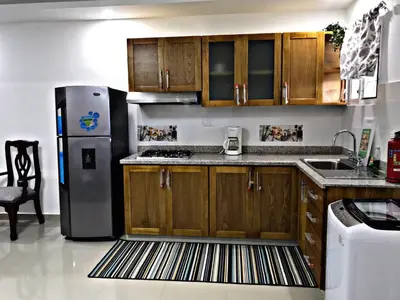 a kitchen with wooden cabinets and a stainless steel refrigerator at Fully Equipped New 1br Apt dt 2mins To Beach in Sosúa