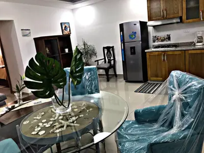 a kitchen with a glass table and two blue chairs at Fully Equipped New 1br Apt dt 2mins To Beach in Sosúa