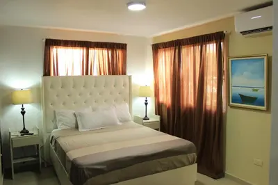 a bedroom with a bed and two lamps and curtains at Fully Equipped New 3br Apt dt 2mins To The Beach in Sosúa