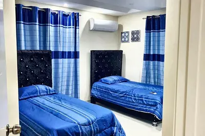 two beds in a room with blue curtains at Spacious house in Santo Domingo Este with garden in Santo Domingo
