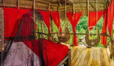 a room with red curtains on a wooden deck at Dominican Tree House Village in El Valle