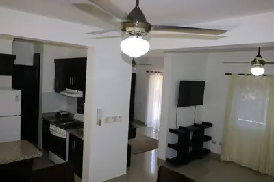 a living room with a ceiling fan and a kitchen at Tu Segundo Hogar en Santiago, La Cuidad CORAZÓN in Santiago de los Caballeros