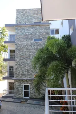 a tall brick building with palm trees in front of it at Tu Segundo Hogar en Santiago, La Cuidad CORAZÓN in Santiago de los Caballeros
