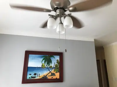 a ceiling fan in a room with a picture of a beach at cómodo first floor in Santiago de los Caballeros
