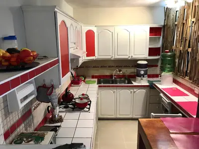 a small kitchen with white cabinets and red accents at Private Rooms-Art Punta Cana in Punta Cana