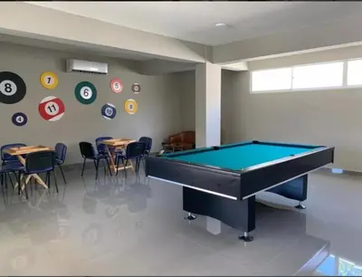 a pool table in a room with tables and chairs at Paraiso de verano in Santiago de los Caballeros