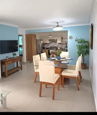 a dining room with a table and white chairs at Paraiso de verano in Santiago de los Caballeros