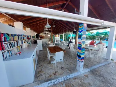 a restaurant with a table and chairs and a book store at Bela Villa Apartment IDA in Bayahibe