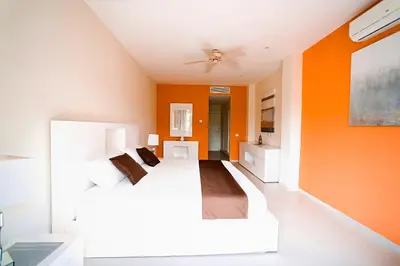 a bedroom with orange walls and white furniture at Luxury Villa Iberosta Del Mar - 4BDR, Private Beach, Pool & Jacuzzi in Punta Cana