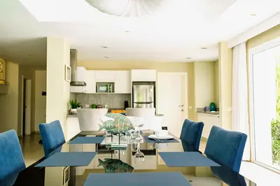 a dining room with a glass table and blue chairs at Luxury Villa Iberosta Del Mar - 4BDR, Private Beach, Pool & Jacuzzi in Punta Cana