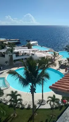 a large pool with palm trees and the ocean at Million View Room Adults Only Resort 1 in La Laguna