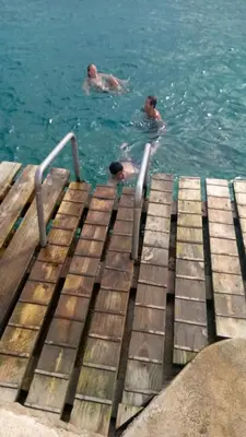 two people swimming in the water on a dock at Million View Room Adults Only Resort 1 in La Laguna