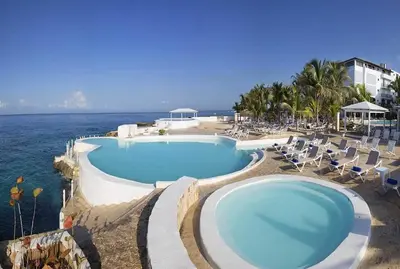 a large swimming pool with chairs and the ocean at Espectacular Apartamento con Vista al Mar Solo Adultos in La Laguna