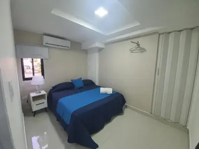 a small bedroom with a blue bed and a window at Malecon Premium Rooms & Hotel in Santo Domingo