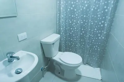 a bathroom with a toilet and a sink and a shower curtain at Malecon Premium Rooms & Hotel in Santo Domingo