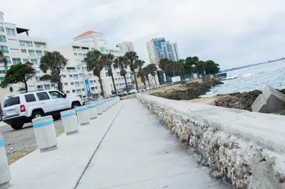 a sidewalk next to the ocean with a white truck at Malecon Premium Rooms & Hotel in Santo Domingo