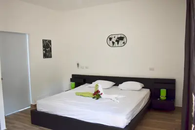 a bedroom with a bed with white sheets and a clock on the wall at Villa Laëti in Las Terrenas