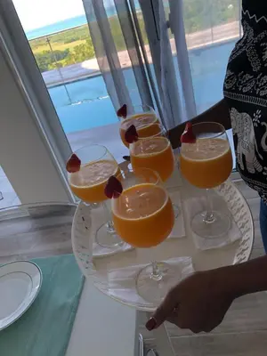 a woman holding a tray with four glasses of orange juice at Villa Laëti in Las Terrenas