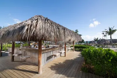a restaurant with benches and a straw umbrella at Dreams Macao Beach Punta Cana - All Inclusive in Punta Cana