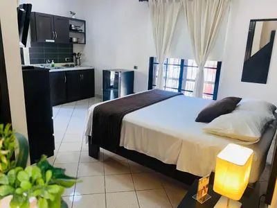 a bedroom with a large bed and a kitchen at Ocean Breeze Studios in Santo Domingo