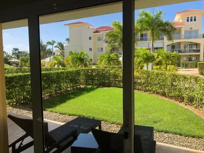 a view from the living room of a resort with a view of a yard at Beautiful One Bedroom unit with pool and Beach club in a Golf Project in Punta Cana