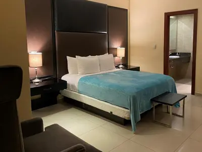 a hotel room with a bed and two lamps and a chair at Ramada by Wyndham Princess Santo Domingo in Santo Domingo