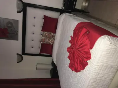 a bed with red and white sheets and a mirror at Hotel Rey in Concepción de La Vega