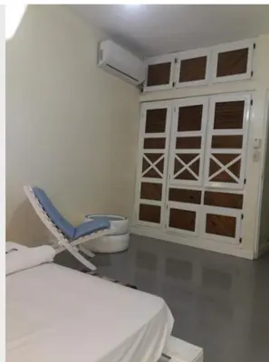 a room with a bed and a chair and a door at Recycled house in Santo Domingo