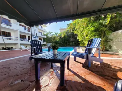 two chairs and a wooden table next to a pool at Calypso Beach Hotel in Boca Chica