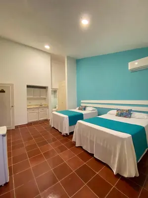 a room with two beds and a tile floor at Calypso Beach Hotel in Boca Chica