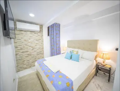 a bedroom with a white bed and a television at 2 Guests 1bed Studio 3min To Beach And Main Street in Sosúa
