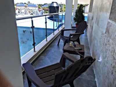 two chairs and a table on a balcony with a pool at Charming 1b Apto Walk To The Beaches Main Street in Sosúa