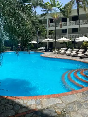 a large blue swimming pool with chairs and umbrellas at Acuarium Suite Resort in Santo Domingo