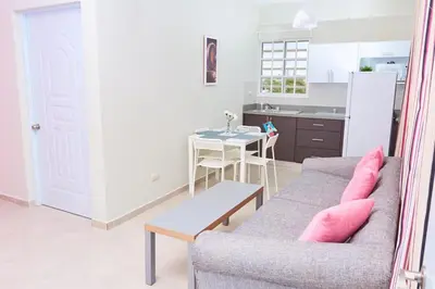 a living room with a couch and a table and a kitchen at Apartahotel MACADANA in Nagua