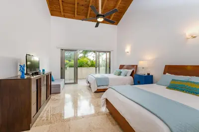 a bedroom with two beds and a flat screen tv at Unique Private Villa with Pools and Golf Cart in La Romana
