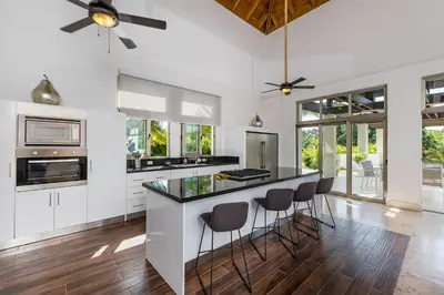 a kitchen with white cabinets and a black island with stools at Unique Private Villa with Pools and Golf Cart in La Romana