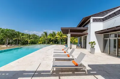 a row of lounge chairs next to a swimming pool at Unique Private Villa with Pools and Golf Cart in La Romana