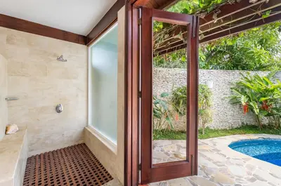 a bathroom with a glass door leading to a pool at Unique Villa with Ocean and River Views - Staff & Golf Carts in La Romana