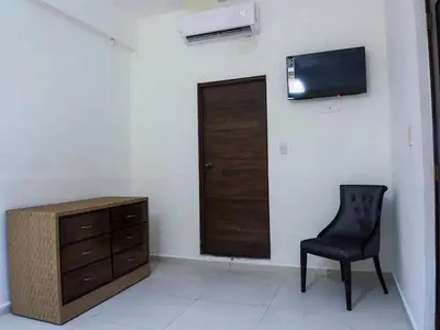 a room with a chair and a dresser and a television at Malecon Cozy - Premium Plus 5 in Santo Domingo