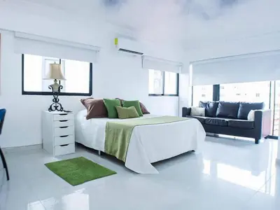 a white bedroom with a large bed and a couch at Malecon Cozy - Premium Plus 10 in Santo Domingo